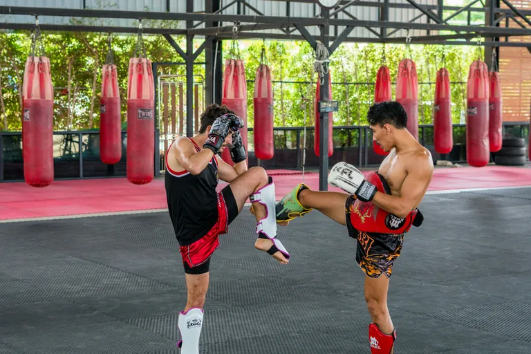Dois alunos treinando chute de muay thai na academia