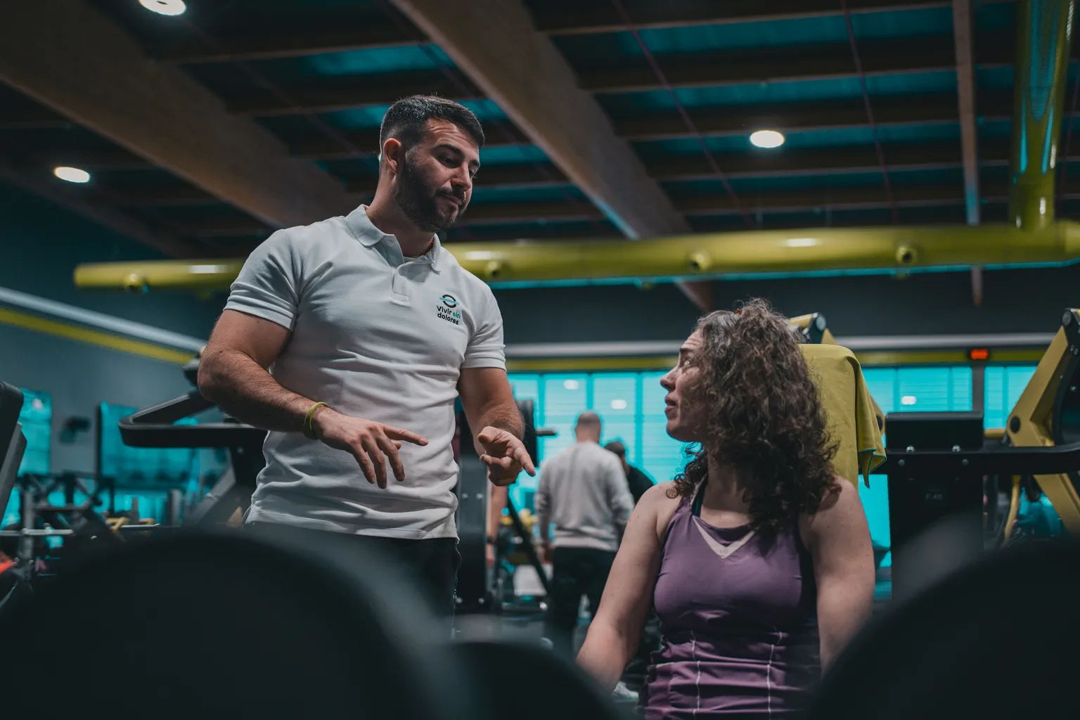 Professor conversando com uma aluna no salão de musculação